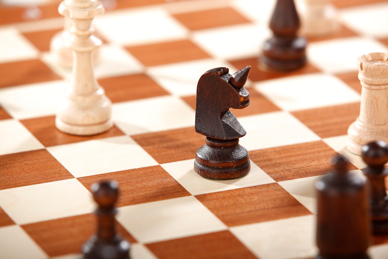 Detailed shot of wooden chess pieces on a classic checkerboard, featuring a knight prominently.